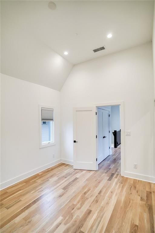 unfurnished room with light wood finished floors, visible vents, high vaulted ceiling, and baseboards