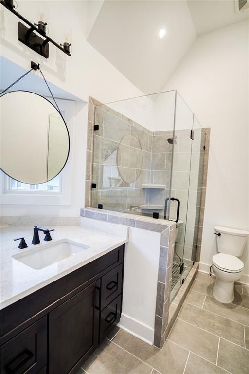 full bath with visible vents, toilet, vaulted ceiling, a stall shower, and vanity