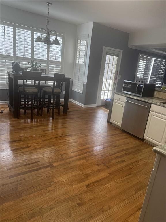 dining space with dark wood finished floors, a wealth of natural light, and a notable chandelier