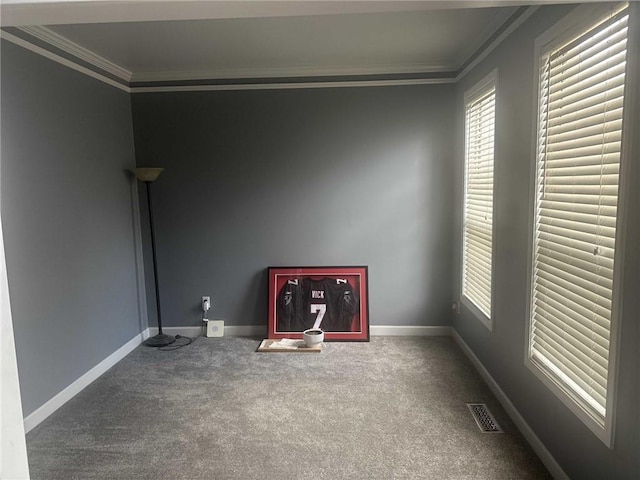 carpeted empty room with a wealth of natural light, visible vents, ornamental molding, and baseboards