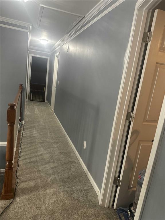 corridor with attic access, baseboards, crown molding, an upstairs landing, and dark carpet