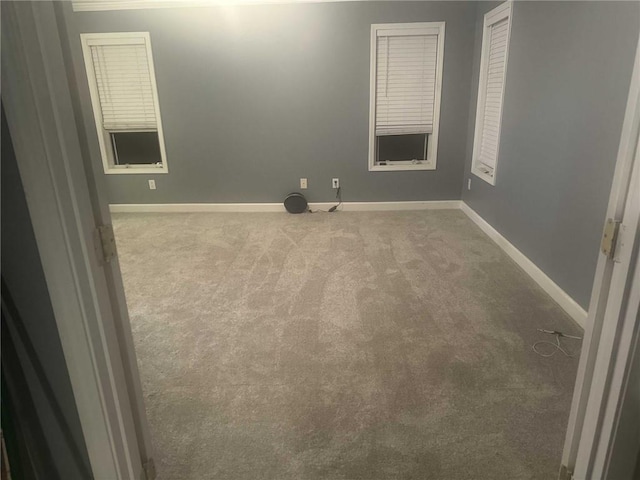 spare room with baseboards and light colored carpet