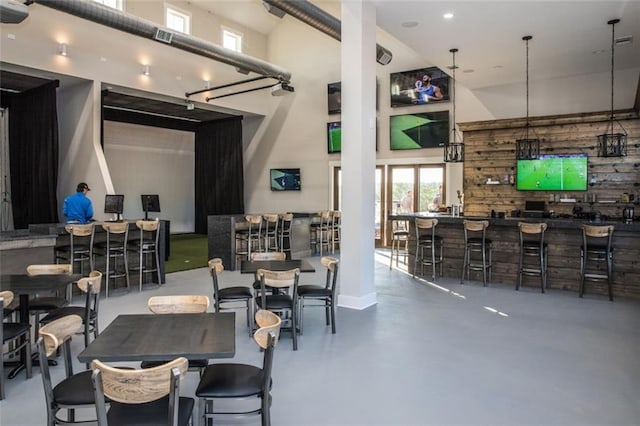 dining room with a towering ceiling and concrete floors