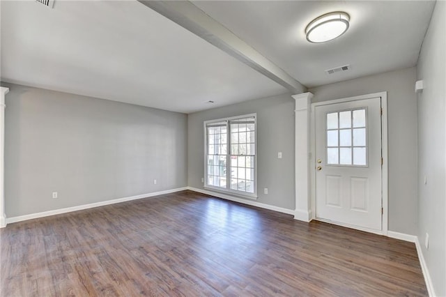 foyer entrance featuring dark wood-style floors, baseboards, visible vents, and ornate columns