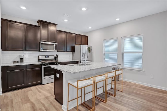 4658 Electric Ave SW, Mableton, GA 30126 - kitchen featuring a sink, light wood-style floors, stainless steel appliances, decorative backsplash, and a center island with sink