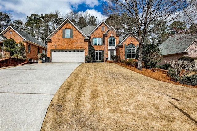 traditional-style home with a garage, a front yard, brick siding, and driveway