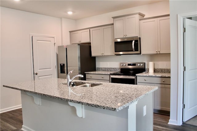 kitchen featuring appliances with stainless steel finishes, sink, light stone counters, and dark hardwood / wood-style floors