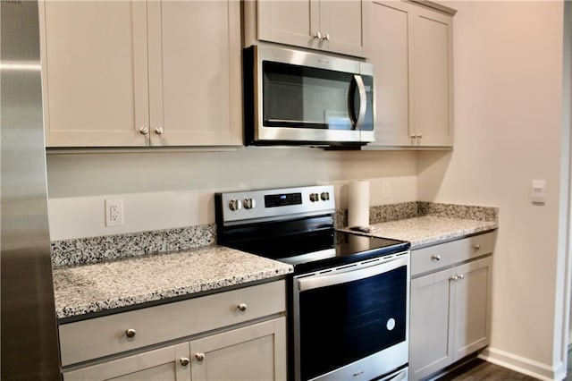 kitchen with stainless steel appliances, dark hardwood / wood-style floors, and light stone counters