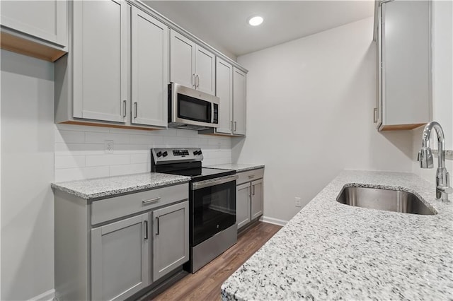 kitchen featuring gray cabinetry, light stone counters, sink, and stainless steel appliances