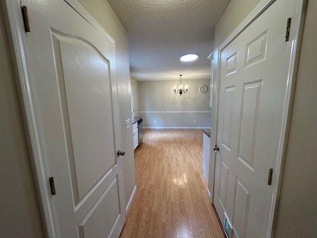 176 Elbert St, Chatsworth, GA 30705 - corridor featuring light wood-style flooring, a chandelier, a textured ceiling, and baseboards