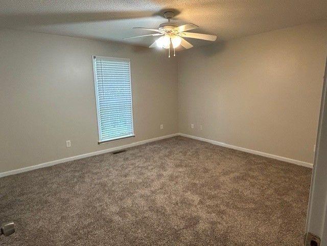 carpeted spare room featuring a ceiling fan and baseboards