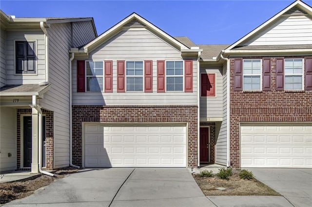 view of property with brick siding, an attached garage, and concrete driveway