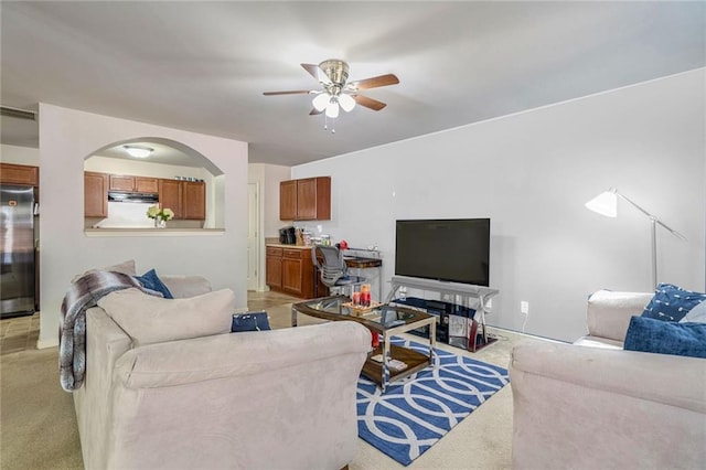 living room with light carpet, visible vents, arched walkways, and ceiling fan