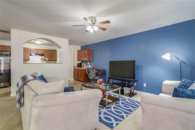 living area with ceiling fan, visible vents, arched walkways, and light carpet