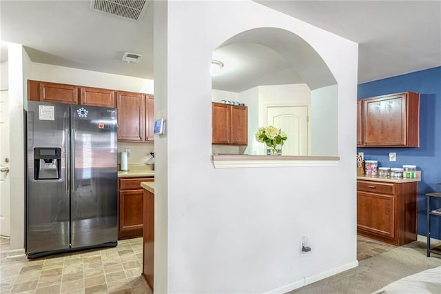 kitchen featuring light countertops, visible vents, stainless steel fridge, and arched walkways