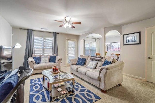 carpeted living room with ceiling fan, arched walkways, visible vents, and baseboards