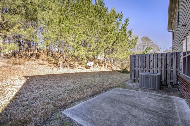 view of yard featuring a patio, fence, and central AC