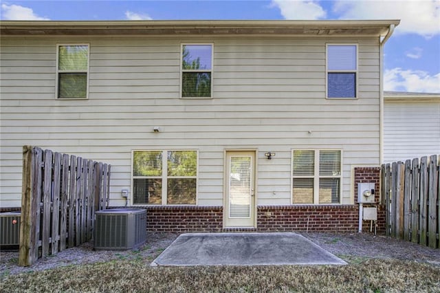 back of house with cooling unit, a patio, brick siding, and fence