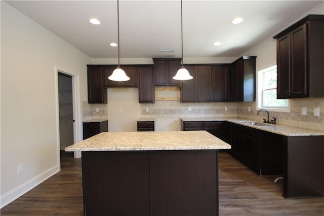 kitchen featuring sink, a kitchen island, dark hardwood / wood-style floors, and decorative light fixtures