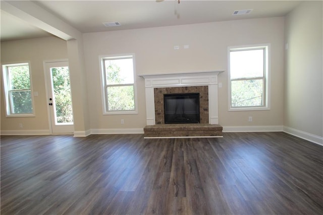 unfurnished living room featuring ceiling fan, dark wood-type flooring, and a brick fireplace