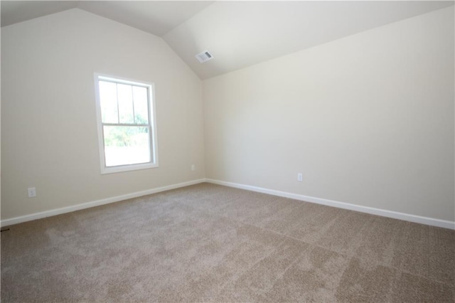 carpeted spare room featuring vaulted ceiling