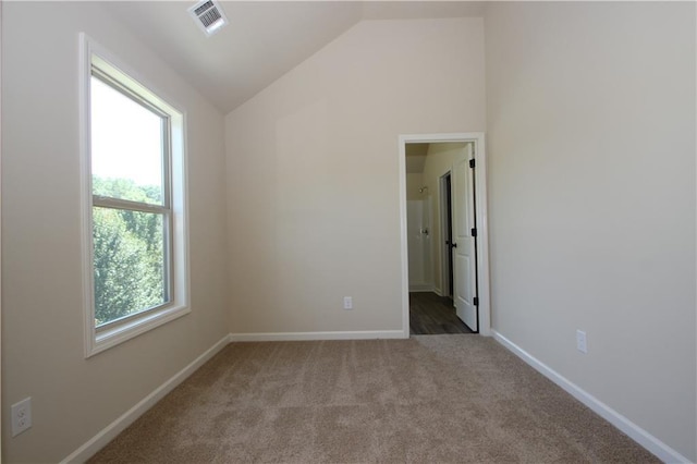 spare room with light carpet, plenty of natural light, and lofted ceiling