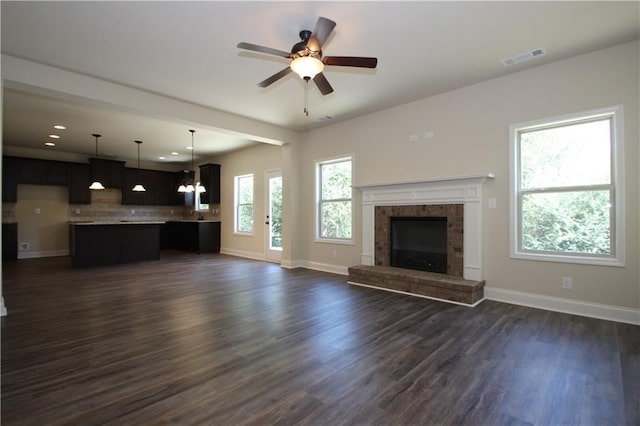 unfurnished living room with ceiling fan with notable chandelier and dark hardwood / wood-style floors