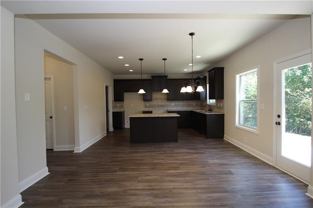 kitchen with a center island, tasteful backsplash, dark hardwood / wood-style flooring, pendant lighting, and a chandelier