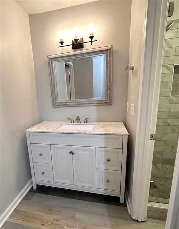 bathroom featuring hardwood / wood-style floors, vanity, and tiled shower