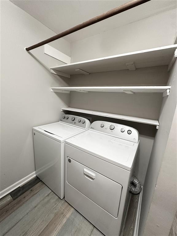 clothes washing area featuring independent washer and dryer and wood-type flooring