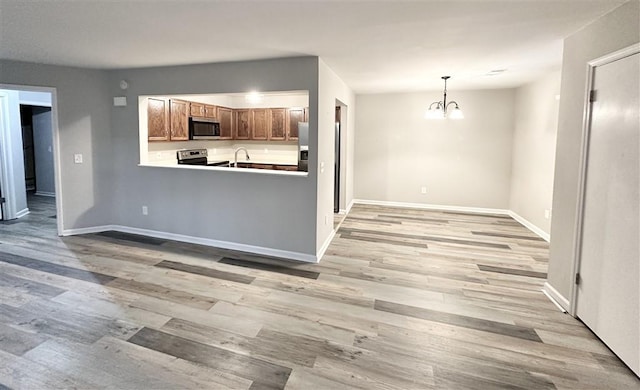 kitchen with sink, light hardwood / wood-style flooring, a notable chandelier, pendant lighting, and appliances with stainless steel finishes