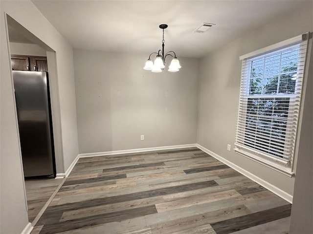 unfurnished dining area featuring a chandelier and dark hardwood / wood-style flooring