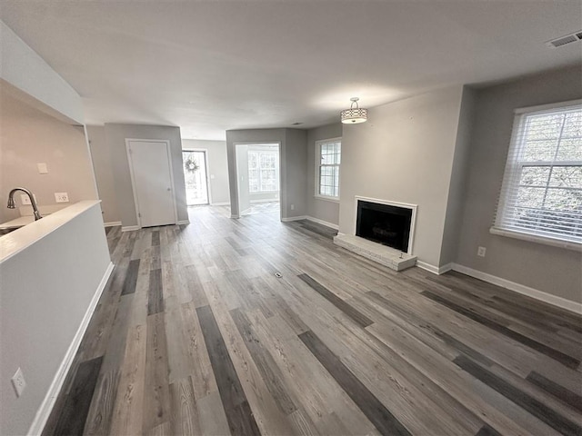 unfurnished living room featuring a wealth of natural light, sink, and dark wood-type flooring