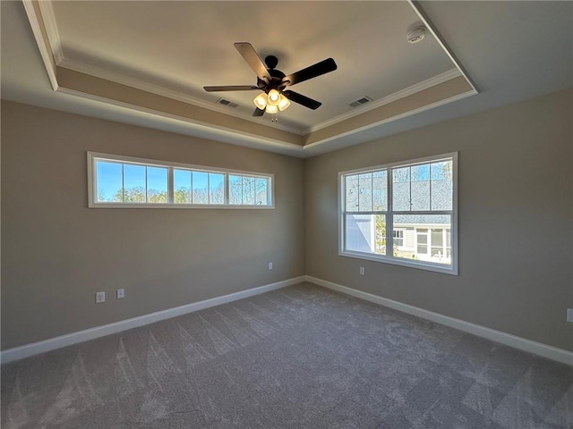 carpeted spare room with a raised ceiling, a ceiling fan, baseboards, visible vents, and ornamental molding