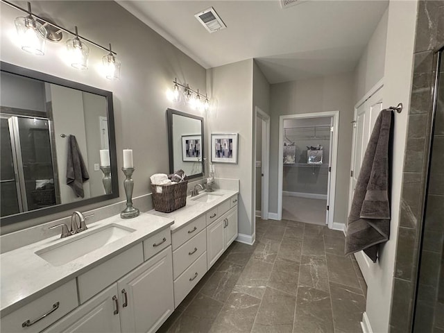 bathroom with double vanity, a shower with door, visible vents, and a sink