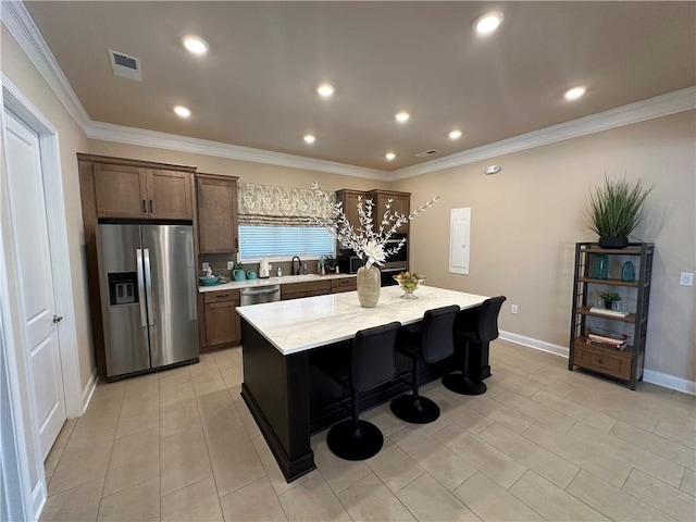 kitchen with visible vents, a center island, a sink, baseboards, and stainless steel appliances