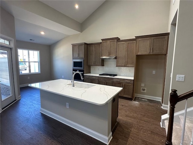 kitchen featuring black gas cooktop, a sink, stainless steel microwave, oven, and dark wood-type flooring