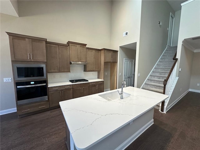 kitchen featuring stainless steel oven, a sink, built in microwave, and dark wood finished floors