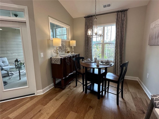 dining room with visible vents, vaulted ceiling, wood finished floors, baseboards, and a notable chandelier