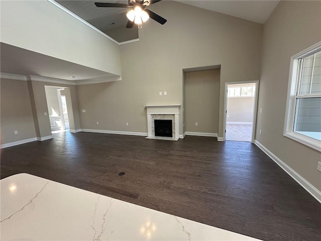 unfurnished living room featuring ceiling fan, a fireplace with flush hearth, high vaulted ceiling, baseboards, and dark wood-type flooring
