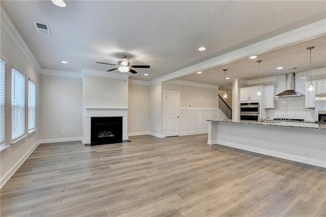 1431 Winding Ridge Trl, Buford, GA 30548 - unfurnished living room featuring light wood-style flooring, ceiling fan, crown molding, a fireplace, and stairs