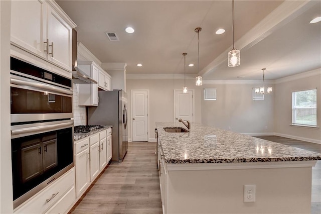 1431 Winding Ridge Trl, Buford, GA 30548 - kitchen with stainless steel appliances, crown molding, a kitchen island with sink, white cabinetry, and light wood-style floors