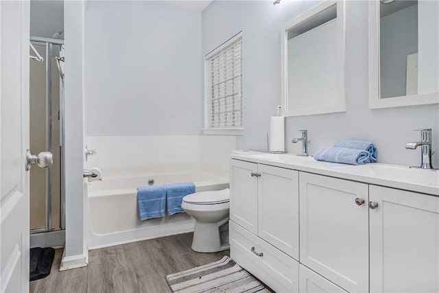 bathroom featuring double vanity, a garden tub, a sink, and wood finished floors