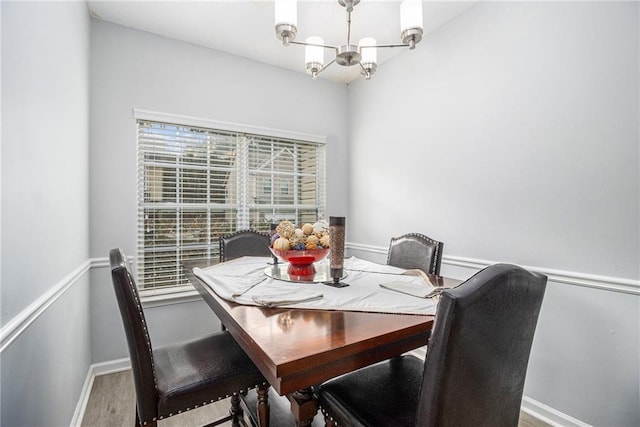 dining space featuring a chandelier, baseboards, and wood finished floors