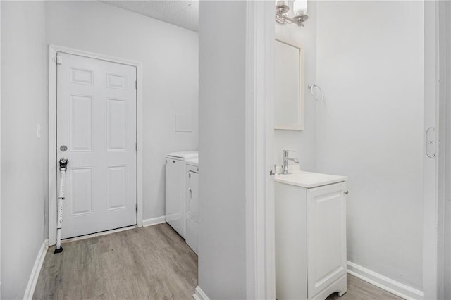 half bath featuring toilet, wood finished floors, vanity, baseboards, and washer and dryer