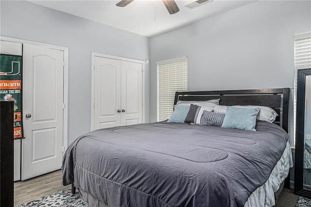 bedroom with ceiling fan, visible vents, and wood finished floors