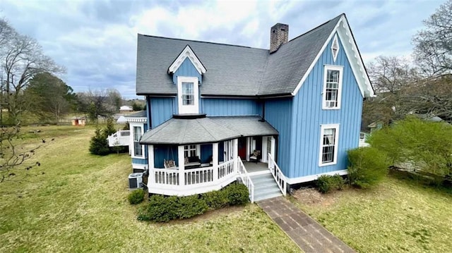 view of front of property featuring a porch, a front yard, a chimney, and central air condition unit