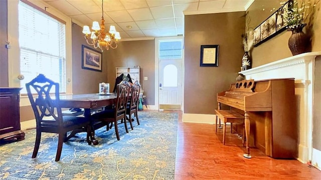 dining area with a chandelier, wood finished floors, baseboards, and ornamental molding