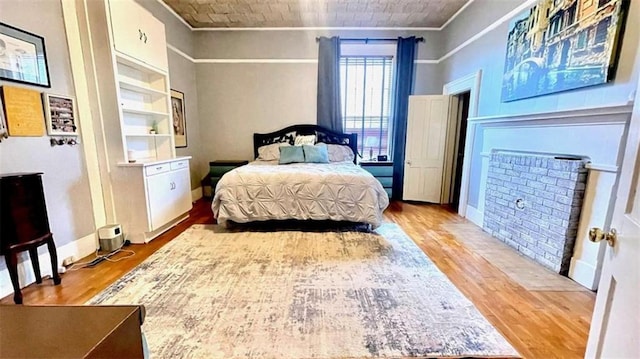 bedroom featuring wood finished floors, ornamental molding, and baseboards