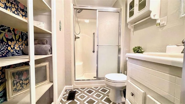 bathroom featuring a shower stall, toilet, and vanity
